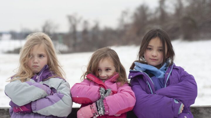 three girls wearing pink and purple winter coats