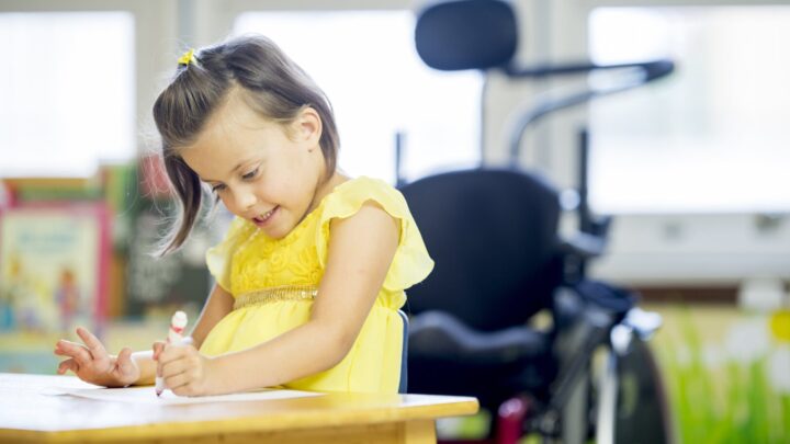 A child is sitting at a table drawing
