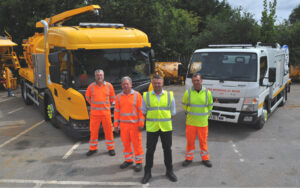 four workers stand in front of new gully cart and jetter