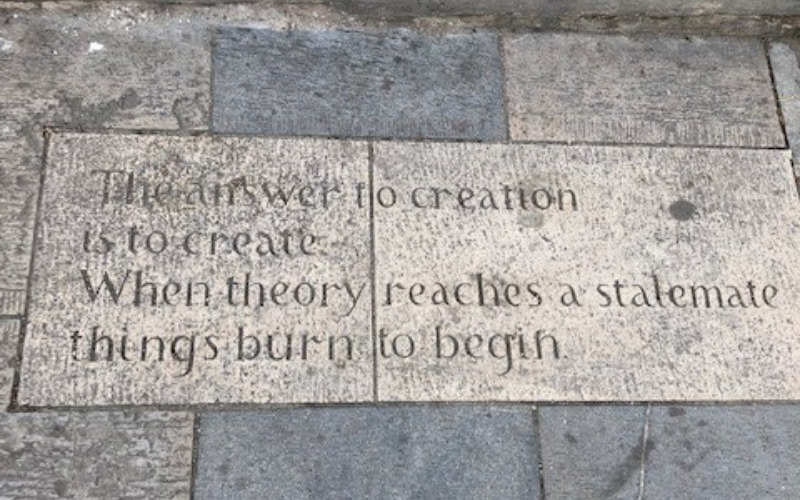 Inscribed slab reads: 'The answer to creation is to create, When theory reaches a stalemate things burn to begin'