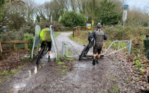 two cyclists struggling to get through access barrier onto trailway