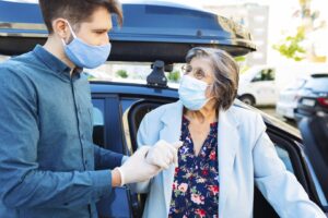 man helping woman in face coverings