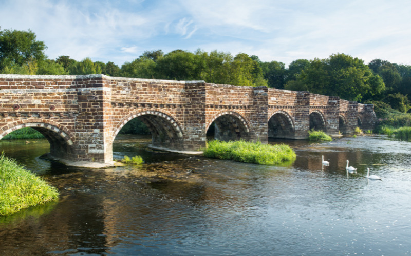white mill bridge with swans swimming underneath
