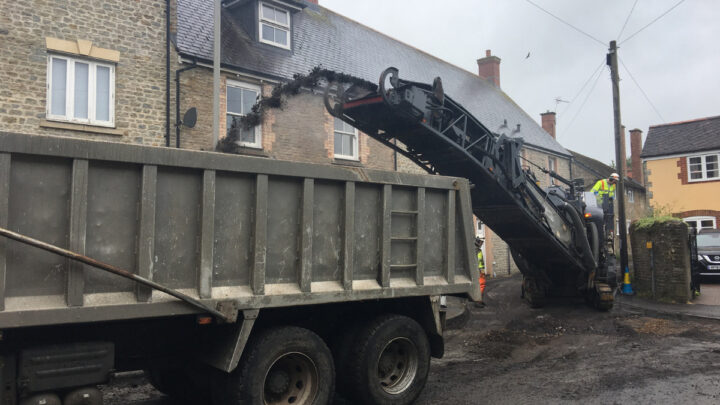 large vehicles resurfacing in narrow street