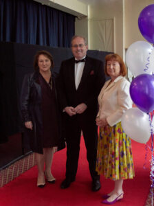 three people stood by blue and white balloons