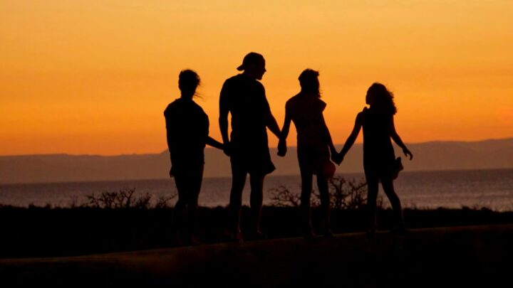 A photo of a family stood in front of a sunset.