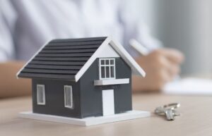 Photo of a model house with person signing papers behind