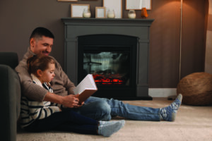 Image of Parent and Child reading a book in front of a fire