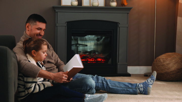 Image of Parent and Child reading a book in front of a fire