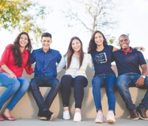 five teenagers smile at the camera