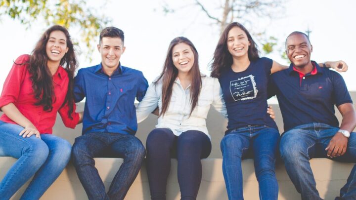 five teenagers smile at the camera