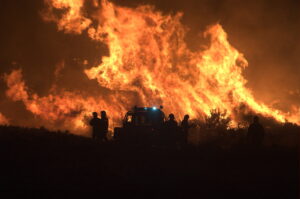 Large heathland fire with Fire and Rescue service in silhouette in the foreground