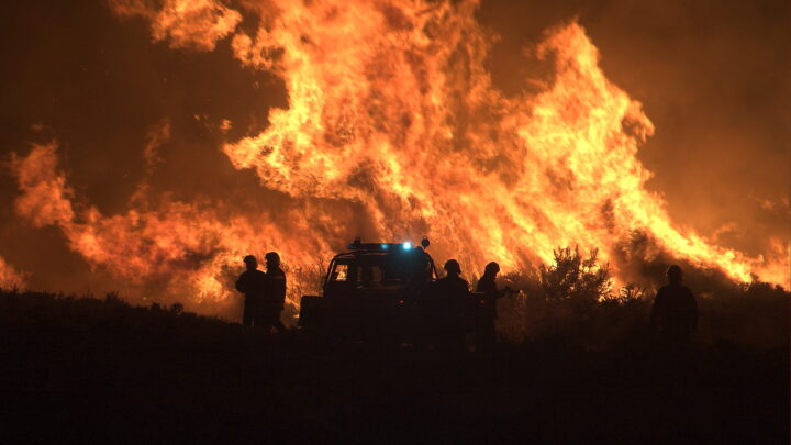 Large heathland fire with Fire and Rescue service in silhouette in the foreground