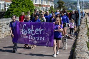 A group of people wearing purple tshirts walking with a banner