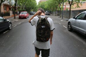 teenager with backpack walking down road