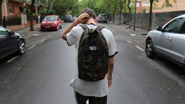 teenager with backpack walking down road
