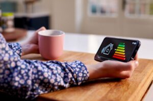 individual sitting in kitchen looking at smart meter to monitor energy efficiency