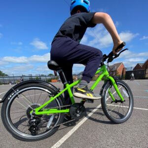 child wearing navy blue clothes and a blue helmet riding a green bicycle