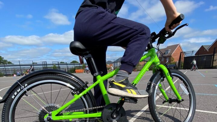 child wearing navy blue clothes and a blue helmet riding a green bicycle
