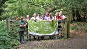 Group of volunteers and ranger standing behind gate posing for picture with green flag