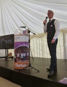 Individual standing on stage speaking in to microphone