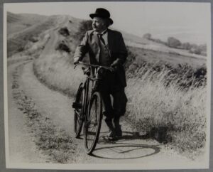Black and white photp of author Thomas Hardy walking with his bicycle