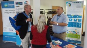 three individuals talking in front of an information stand